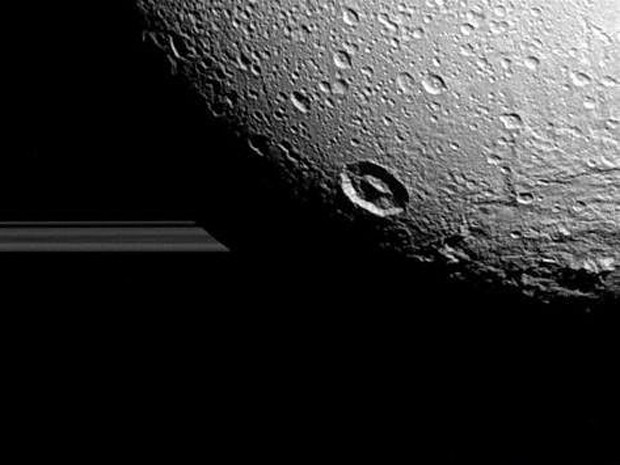 A lua Dione fotografada pela sonda Cassini com os anéis de Saturno ao fundo (Foto: Nasa)