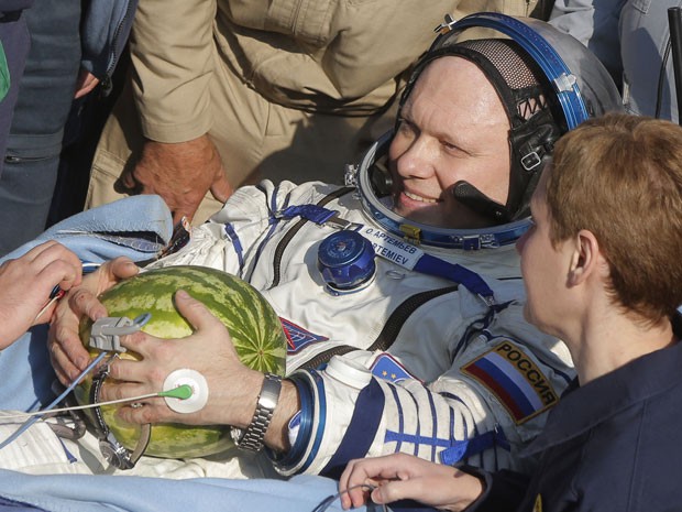 O cosmonauta russo Oleg Artemiev é atendido por médicos e segura uma melancia ao sair da Soyuz TMA-12M (Foto: Maxim Shipeinkov/AFP)