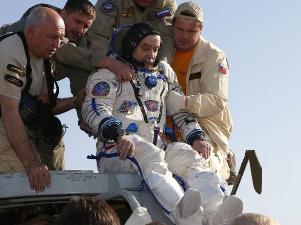 Membro da tripulação, o cosmonauta russo Mikhail Tyurin é ajudado após o desembarque no Cazaquistão (Foto: Dmitry Lovetsky/Pool/Reuters)