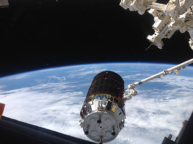 Veículo de carga japonês Kounotori é visto se aproximando da ISS. Ao fundo, aparecem a Terra e a escuridão do espaço (Foto: Nasa/AP)