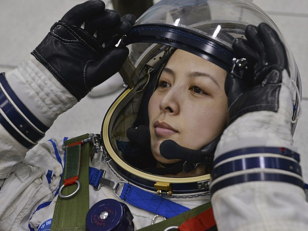 Astronauta chinesa Wang Yaping ajusta o capacete espacial durante treinamento em Pequim no sábado (8) (Foto: Reuters)