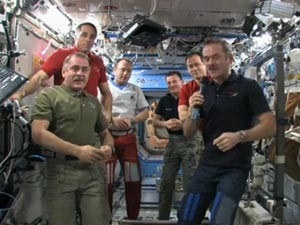 Chris Hadfield, com o microfone, passa o comando da missão para Pavel Vinogradov, à esquerda (Foto: Nasa TV/Reprodução)