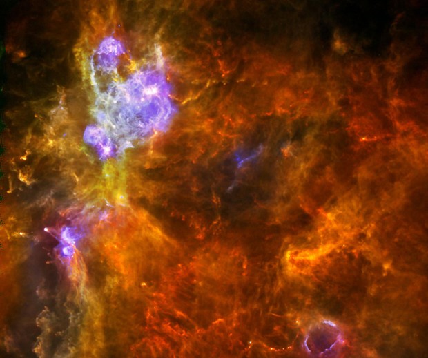 Imagem divulgada pela agência espacial americana (Nasa) nesta segunda-feira (1º) mostra um 'berçário' gigante de estrelas chamado W3, situado a 6,2 mil anos-luz de uma das principais estruturas da Via Láctea. As estrelas em formação que possuem pouca massa podem ser identificadas como pequenos pontos amarelos na área avermelhada da imagem (Foto: ESA/Nasa/AFP)