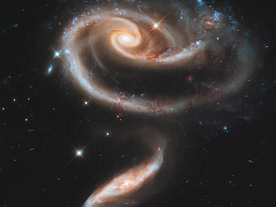 Disco da galáxia UGC 1810 é distorcido pela ação de uma galáxia menor; pontos azuis estrelas jovens
