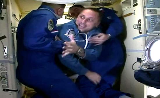 O comandante russo Anton Shkaplerov recebe ajuda de colegas para entrar na estação espacial internacional 