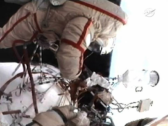 Dois cosmonautas instalam equipamento experimental na parte externa da Estação Espacial Internacional