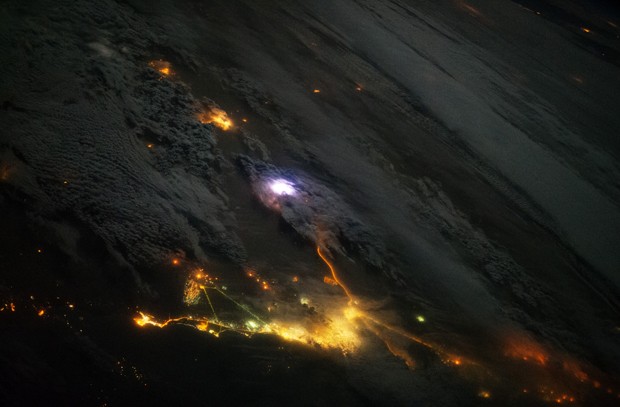 Foto tirada a partir da ISS mostra região entre Kwuait e Arábia Saudita: um relâmpago é visto no centro da imagem (luz branca); cidades podem ser vistas na parte inferior e superior da imagem (luzes amarelas)    (Foto: Nasa/Divulgação)