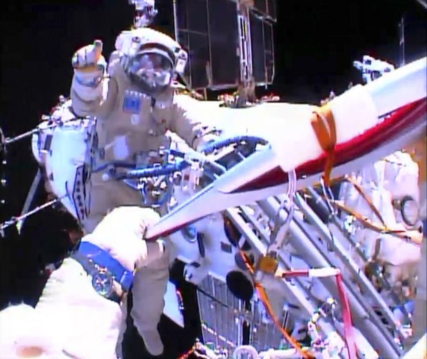 Astronauta russo Oleg Kotov segura tocha olímpica enquanto recebe instruções do russo Sergei Ryazansky do lado de fora da Estação Espacial Internacional (Foto: Nasa/Reuters)