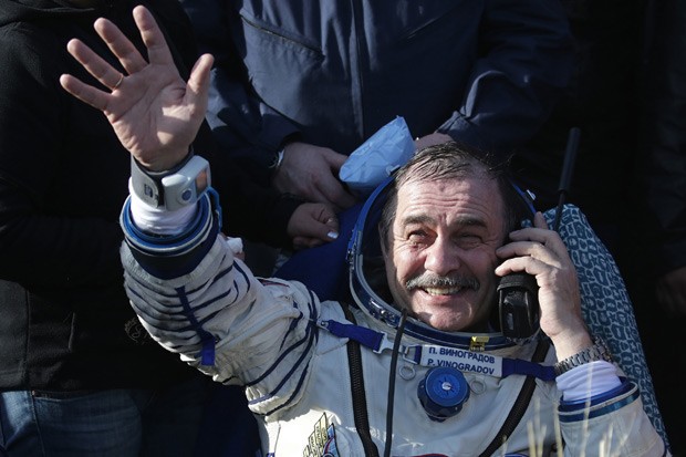 Cosmonauta  Pavel Vinogradov acena logo depois de pousar na Terra, após missão espacial. (Foto: AFP Photo/Pool/Maxim Shipenkov)