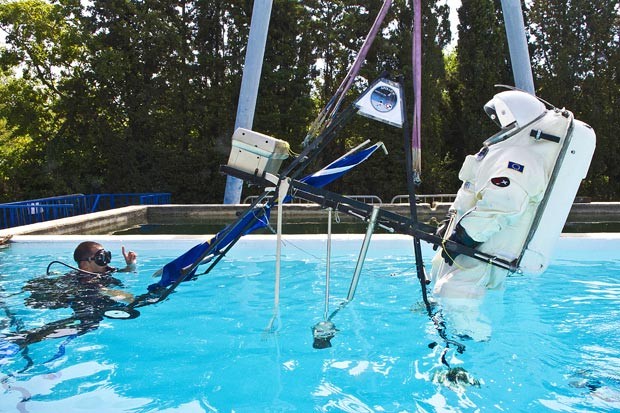 Equipamento carrega astronauta com traje espacial para dentro da piscina de treinamento. (Foto: AFP Photo/Boris Horvat)