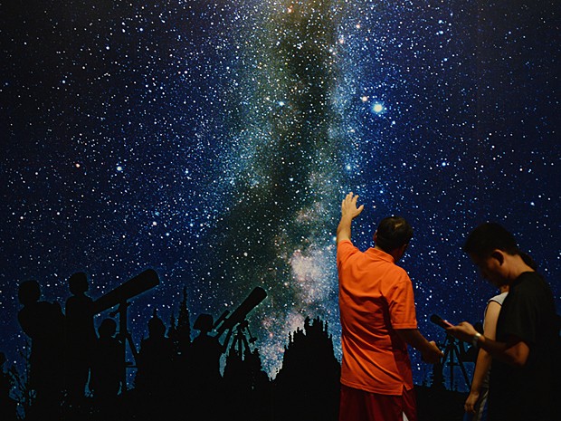 Jovens observam 'céu' estrelado durante exposição nesta sexta-feira (30) (Foto: Mark Ralston/AFP)