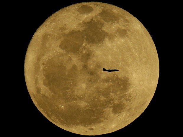 Silhueta de avião é vista em frente à lua no céu de Phoenix, nos EUA. (Foto: Charlie Riedel/AP)